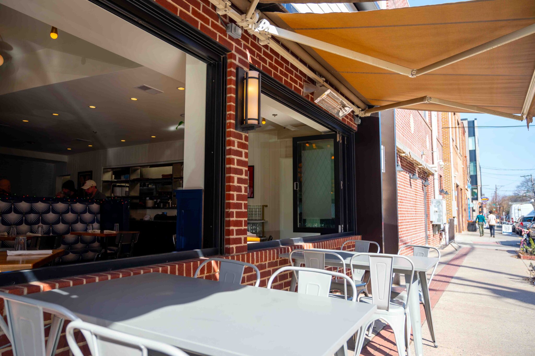 Retractable commercial awning creating comfortable outdoor dining space for restaurant customers
